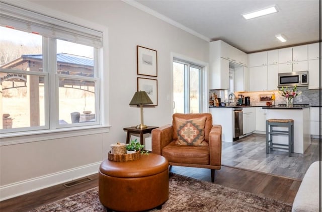 sitting room with visible vents, crown molding, dark wood-type flooring, and baseboards