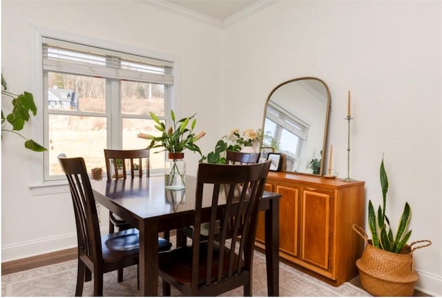 dining space with light wood-style floors, baseboards, and ornamental molding