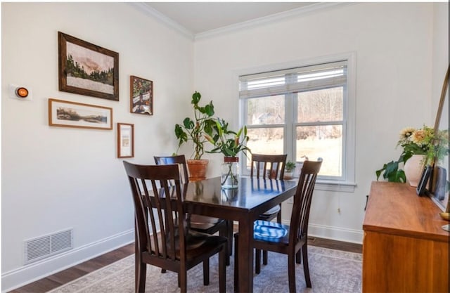 dining room with dark wood-type flooring, baseboards, visible vents, and ornamental molding