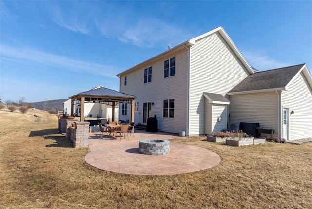 rear view of house with a gazebo, a patio area, an outdoor fire pit, and a yard