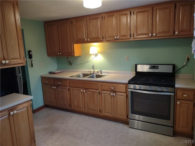 kitchen featuring brown cabinets, light countertops, stainless steel range with gas cooktop, and a sink