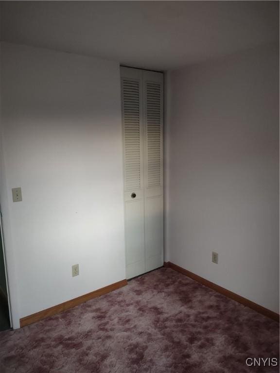 unfurnished bedroom featuring a closet, baseboards, and carpet flooring