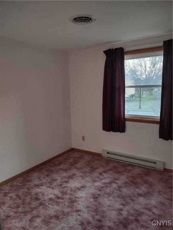 empty room with a baseboard heating unit, carpet, visible vents, and baseboards