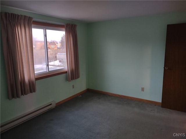 empty room with a baseboard heating unit, carpet, and baseboards