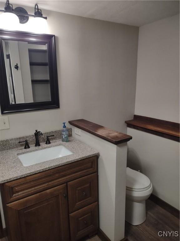 half bathroom with vanity, toilet, and wood finished floors