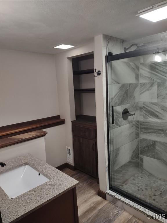 bathroom with vanity, visible vents, wood finished floors, and a stall shower