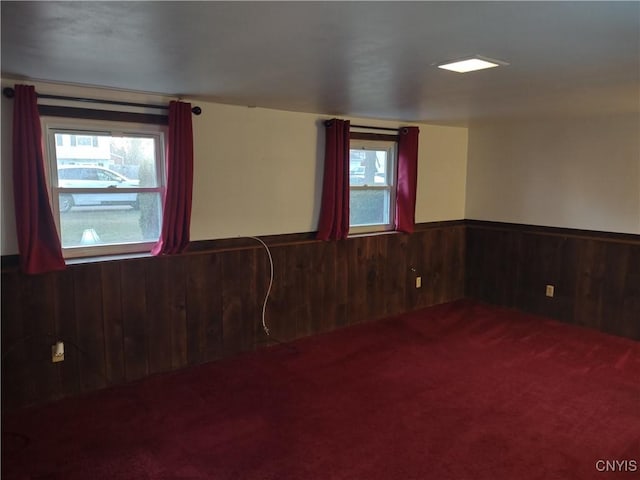 spare room with a wainscoted wall, wooden walls, and carpet flooring