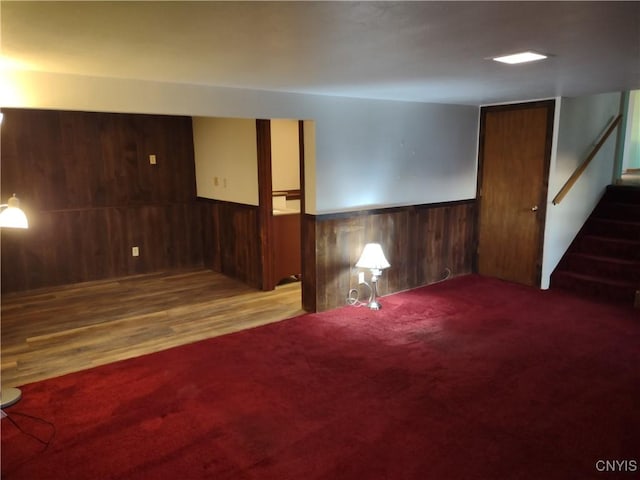 interior space featuring wainscoting, wood walls, stairs, and carpet floors