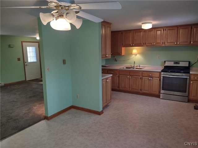 kitchen featuring light carpet, a ceiling fan, a sink, light countertops, and stainless steel gas range