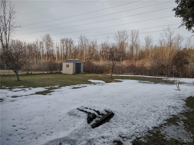 yard layered in snow with a storage unit, an outbuilding, and a fenced backyard