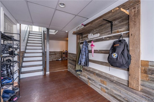 interior space with wood finished floors, stairway, wooden walls, wainscoting, and a paneled ceiling