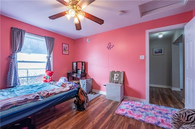 bedroom with baseboards, attic access, wood finished floors, and a ceiling fan