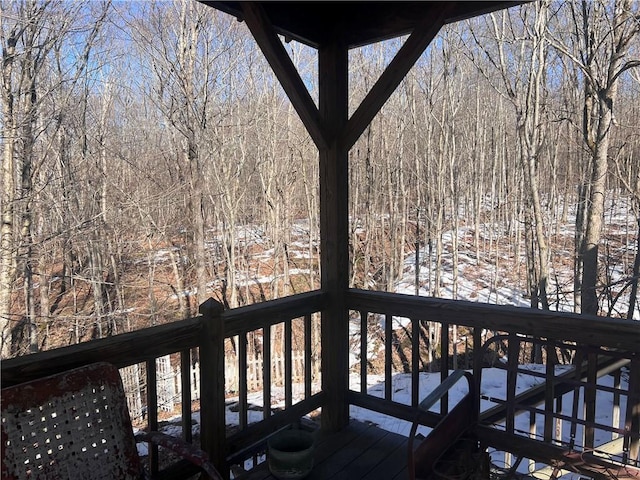 snow covered deck with a wooded view