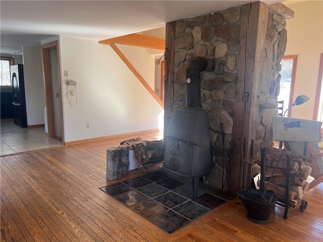 details with baseboards, wood finished floors, a wood stove, and freestanding refrigerator