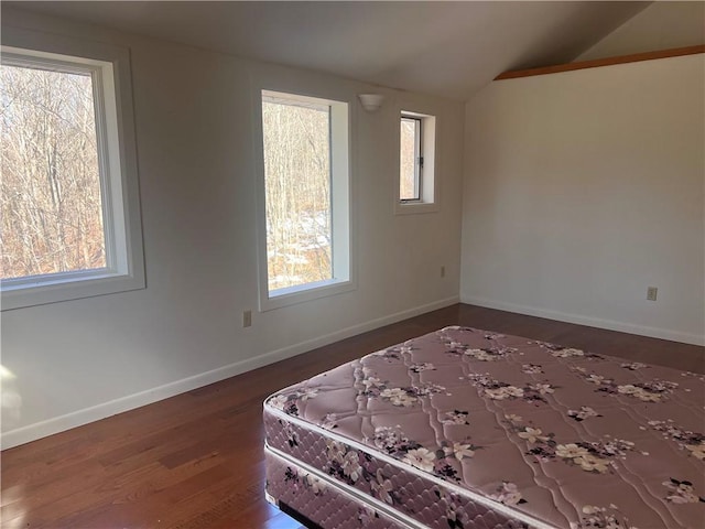 unfurnished bedroom featuring vaulted ceiling, wood finished floors, and baseboards