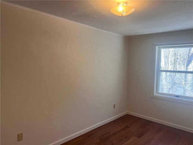 spare room featuring crown molding, dark wood-style floors, and baseboards