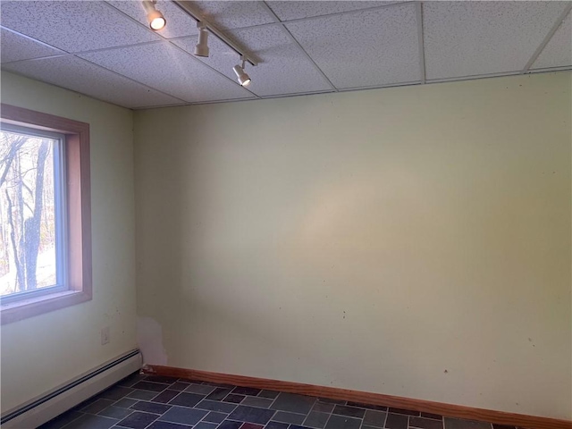 unfurnished room with a paneled ceiling, baseboards, and baseboard heating