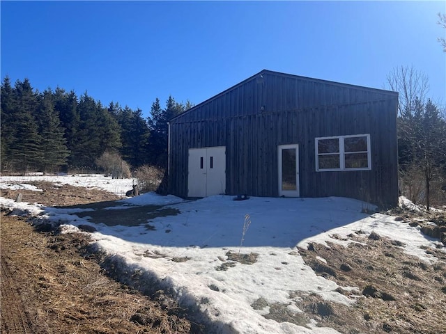 snow covered structure featuring an outbuilding