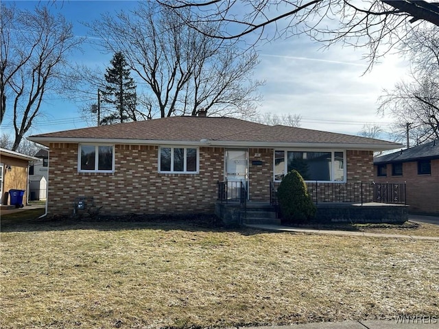 single story home with brick siding, a chimney, a front yard, and roof with shingles