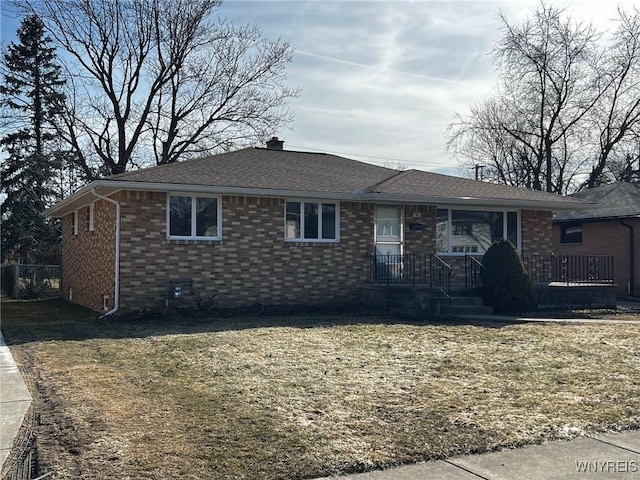 ranch-style home featuring a front lawn, brick siding, roof with shingles, and a chimney