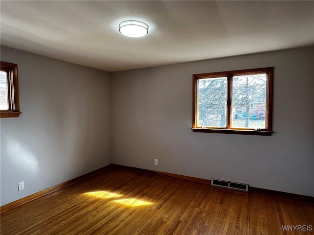 spare room featuring visible vents, dark wood-type flooring, and baseboards