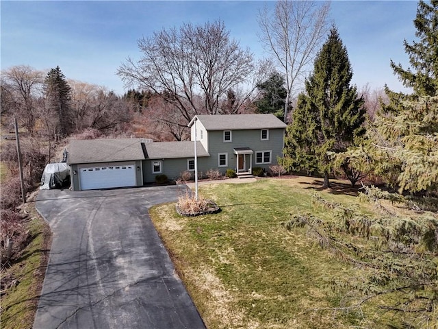 traditional-style home featuring aphalt driveway, an attached garage, and a front lawn