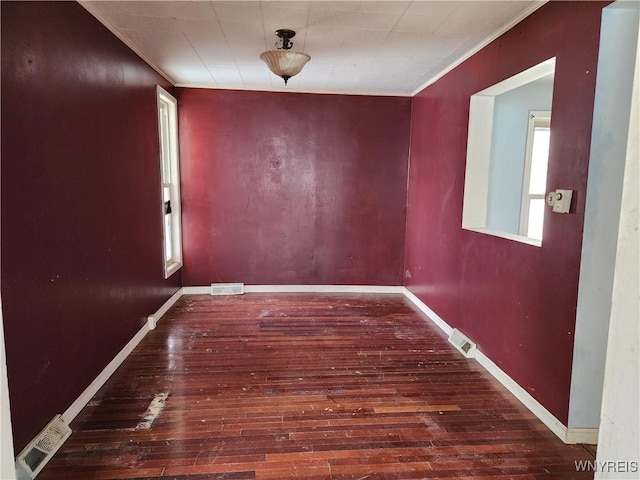 unfurnished dining area featuring visible vents, ornamental molding, baseboards, and wood-type flooring