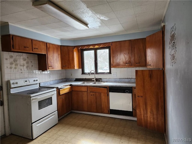 kitchen with a sink, white appliances, light floors, and brown cabinetry