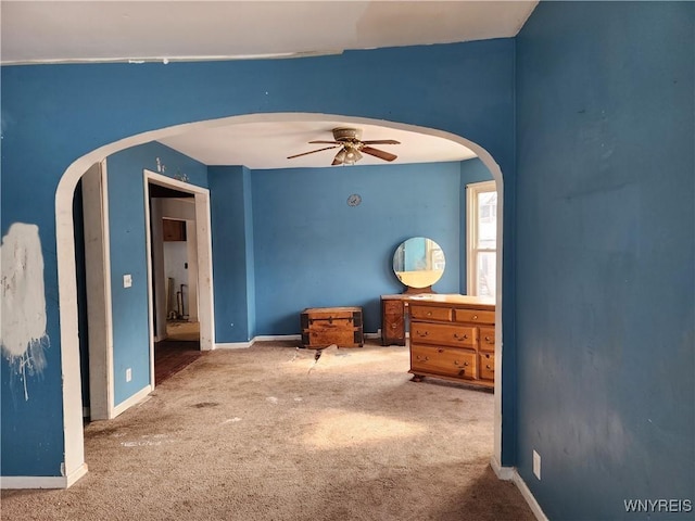 bedroom with arched walkways, carpet flooring, and baseboards