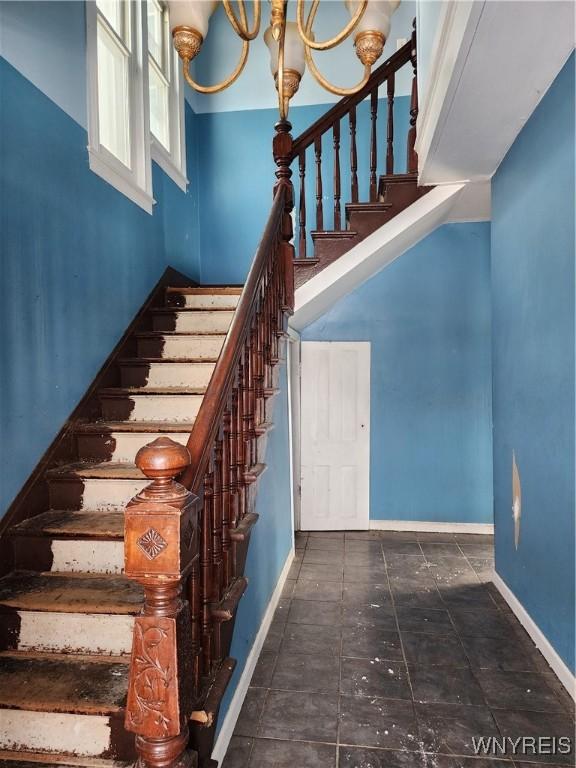 stairway with a notable chandelier and baseboards