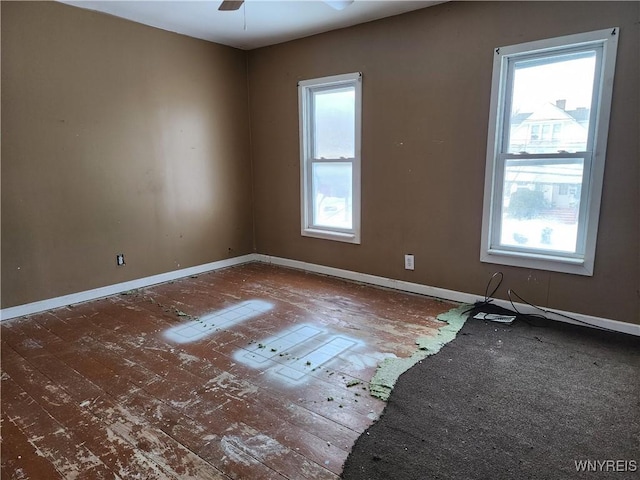 spare room featuring plenty of natural light, ceiling fan, and baseboards