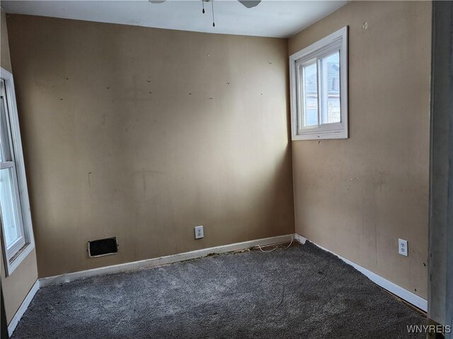 carpeted spare room featuring baseboards and a ceiling fan