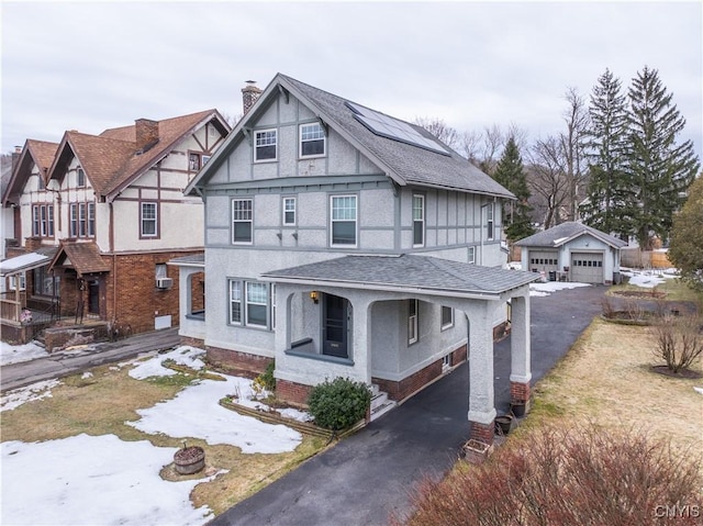english style home with a shingled roof, a chimney, an outdoor structure, stucco siding, and a detached garage