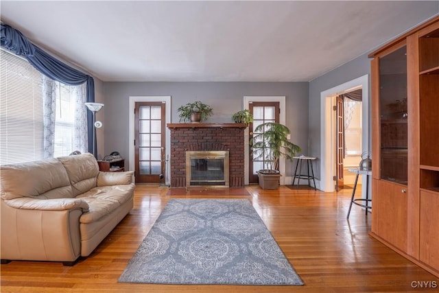 living room featuring a brick fireplace and wood finished floors