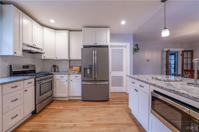kitchen with white cabinetry, under cabinet range hood, light wood-style floors, and appliances with stainless steel finishes