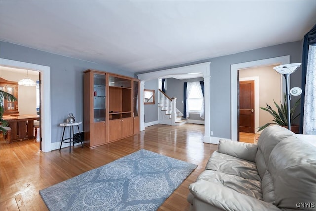 living area with a notable chandelier, stairs, baseboards, and wood finished floors