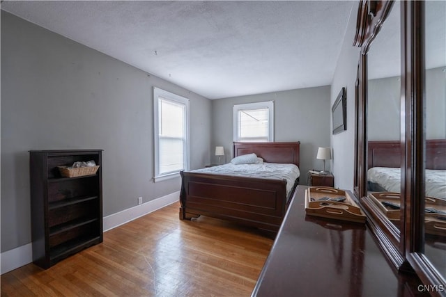 bedroom with wood finished floors, baseboards, and a textured ceiling