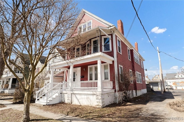 view of front of home featuring a porch, a balcony, and a chimney