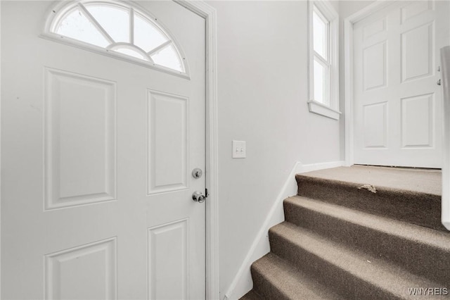 foyer entrance featuring stairway and baseboards