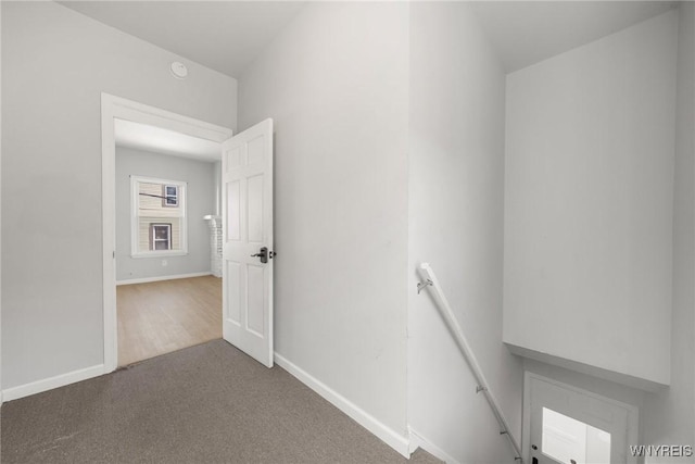 hall featuring carpet flooring, an upstairs landing, and baseboards