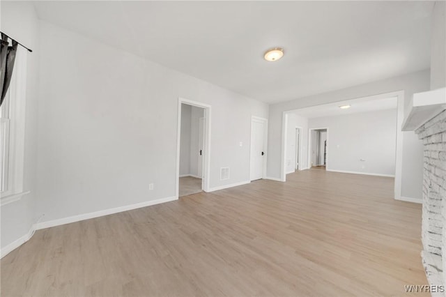 unfurnished living room with visible vents, baseboards, and light wood-type flooring