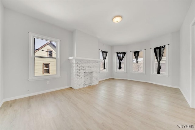 unfurnished living room with a fireplace, baseboards, and light wood finished floors