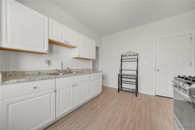 kitchen with visible vents, stainless steel gas range, light wood-style floors, white cabinetry, and a sink