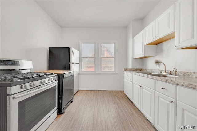 kitchen with dishwashing machine, light wood-style floors, white cabinets, stainless steel gas range, and a sink