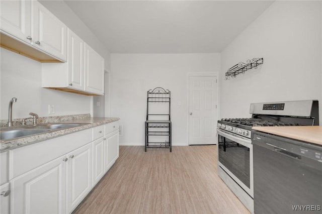 kitchen with gas range, dishwasher, light countertops, light wood-style floors, and a sink