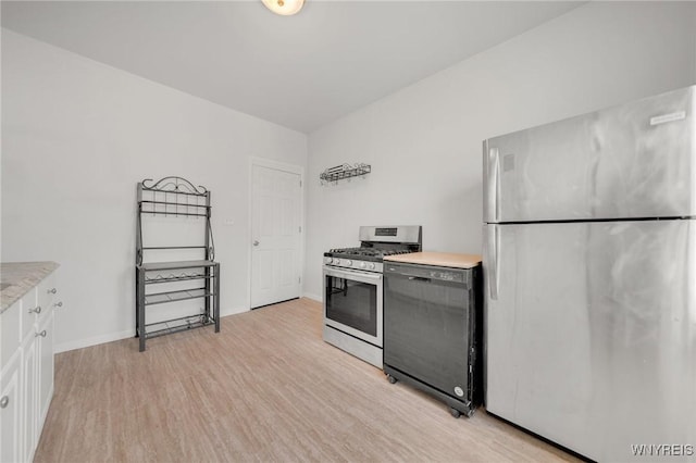 kitchen featuring light wood-type flooring, appliances with stainless steel finishes, white cabinets, light countertops, and baseboards