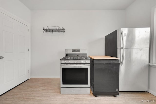 kitchen with stainless steel appliances, baseboards, light countertops, and light wood finished floors