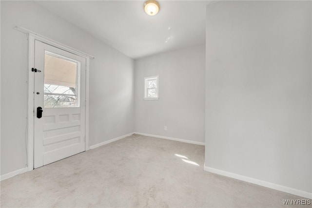 empty room featuring a wealth of natural light, baseboards, and carpet