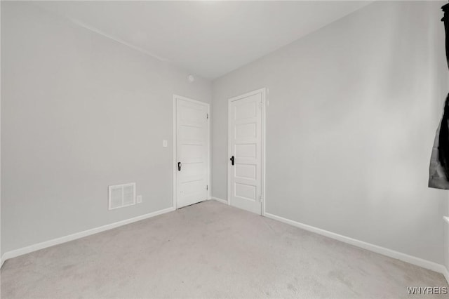 empty room with light colored carpet, baseboards, and visible vents