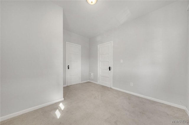 empty room featuring baseboards and light colored carpet